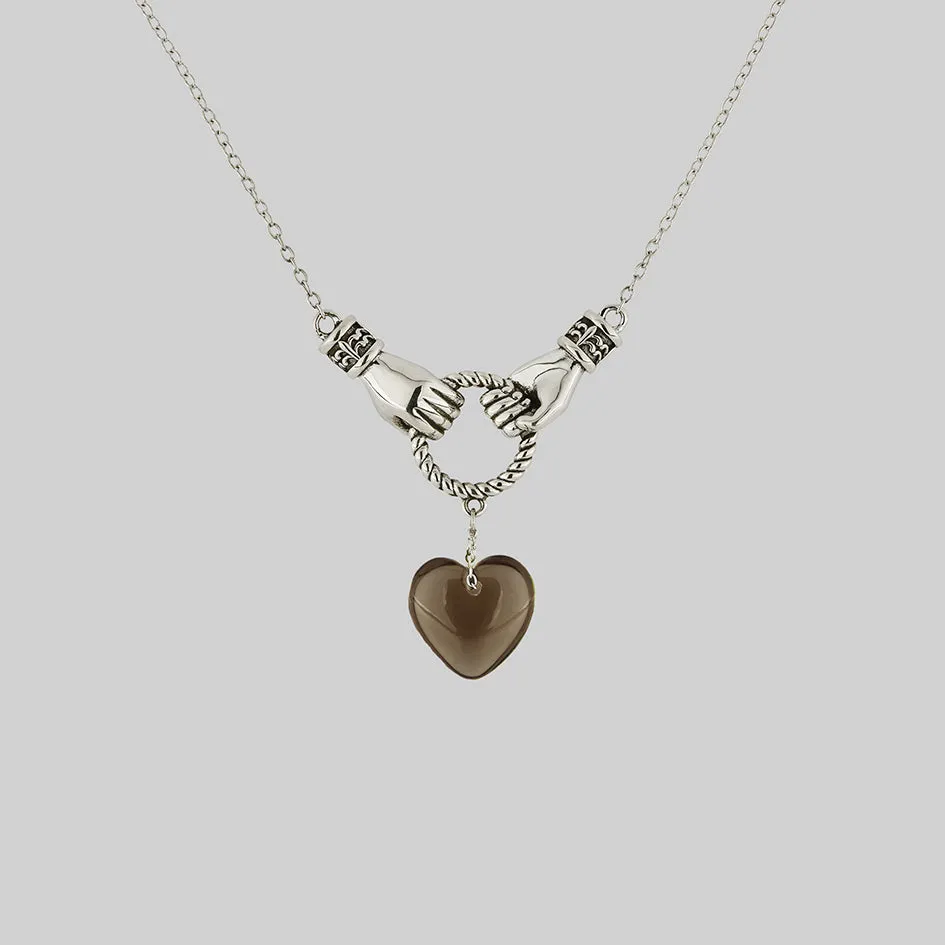 UNITE. Hand Grasping Smoke-Black Glass Heart Necklace - Silver